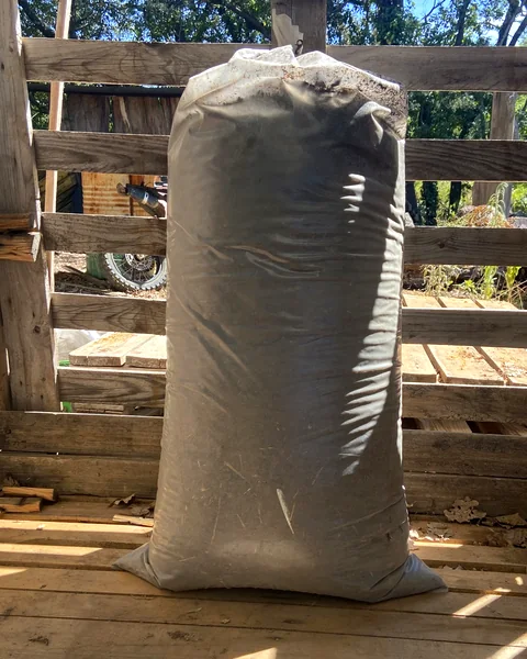 Grand sac de 30 kg de fumier de Migon, sous l'abri de l'atelier à Murles